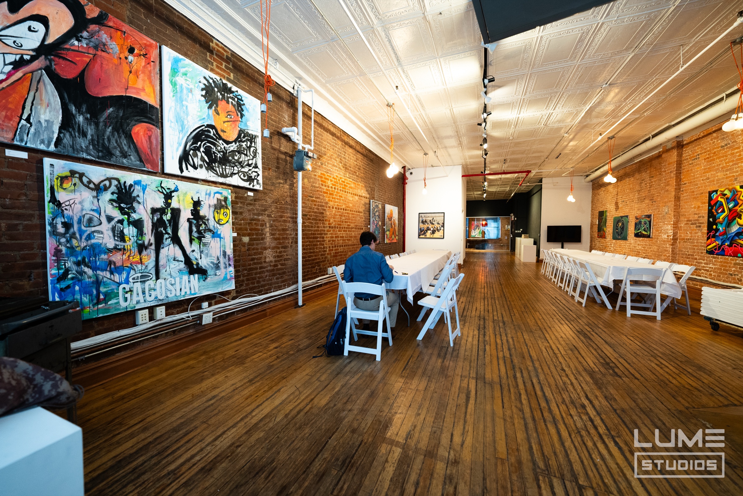 Long white banquet table in a brick walled loft with a tin ceiling and large graffiti style paintings