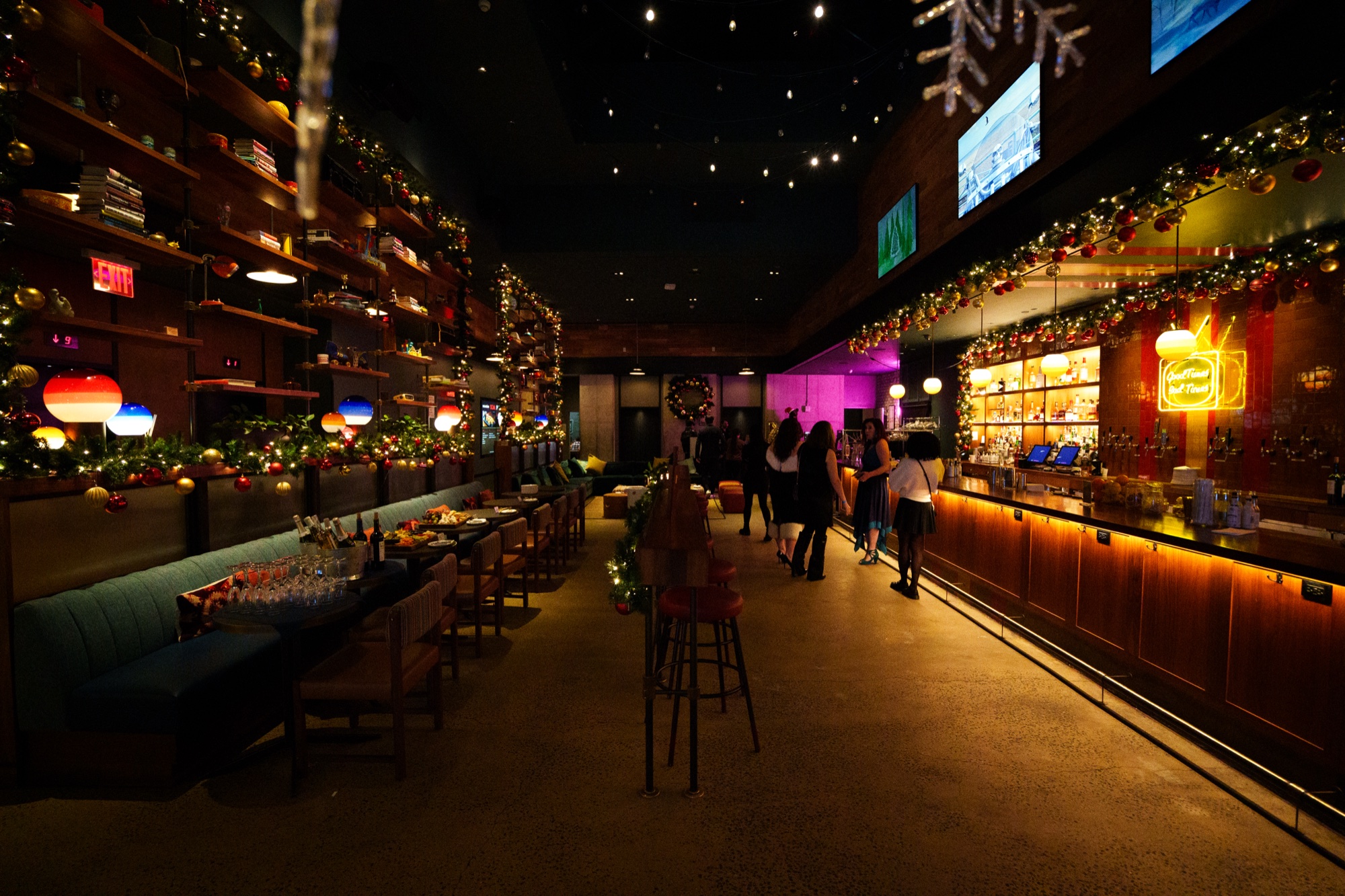 A long bar lined with garlands and coloured lanterns under a starry ceiling, guests gathered at the far end