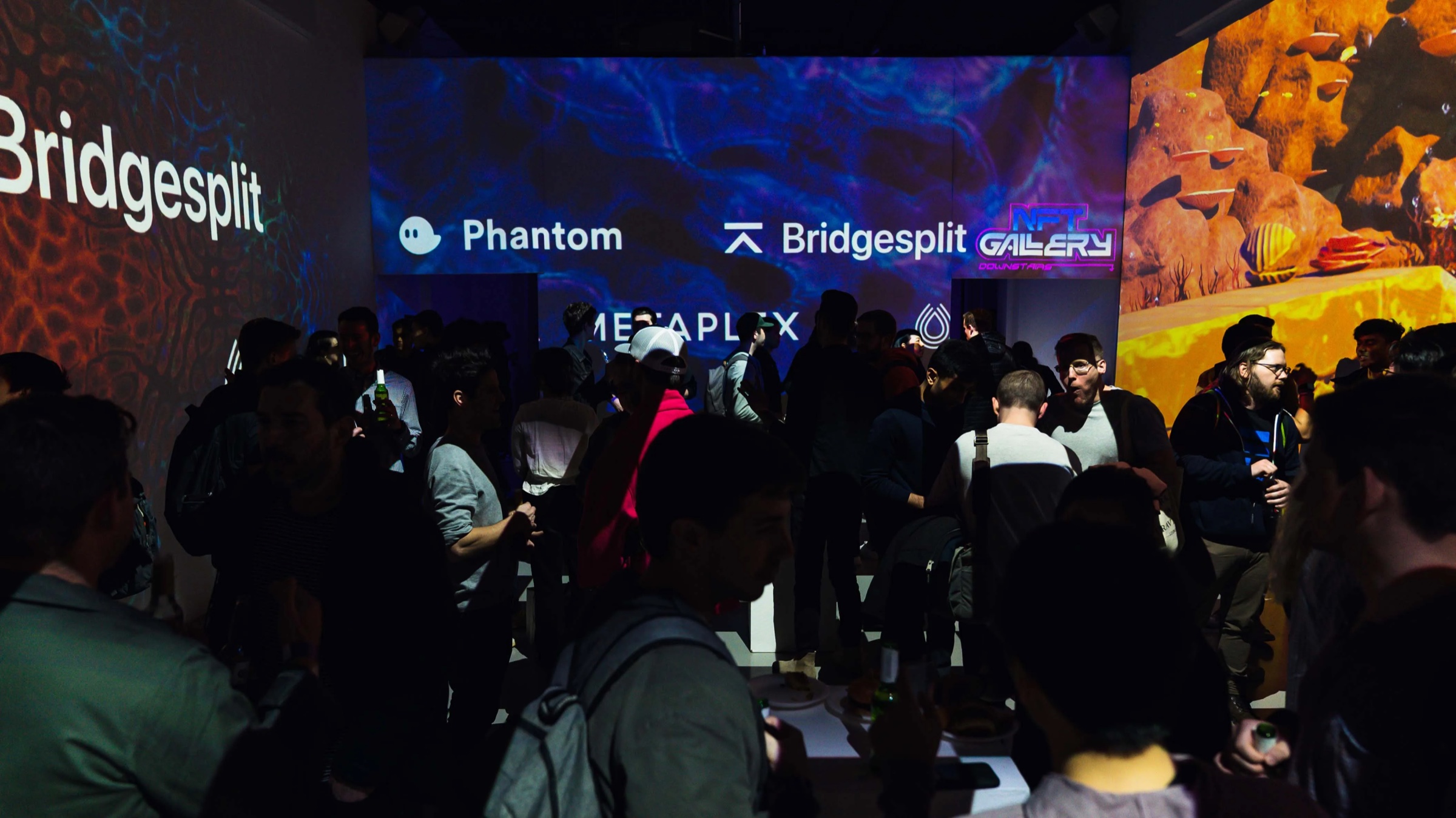 Crowd fills the Metaplex party beneath Phantom and Bridgesplit sponsor projections