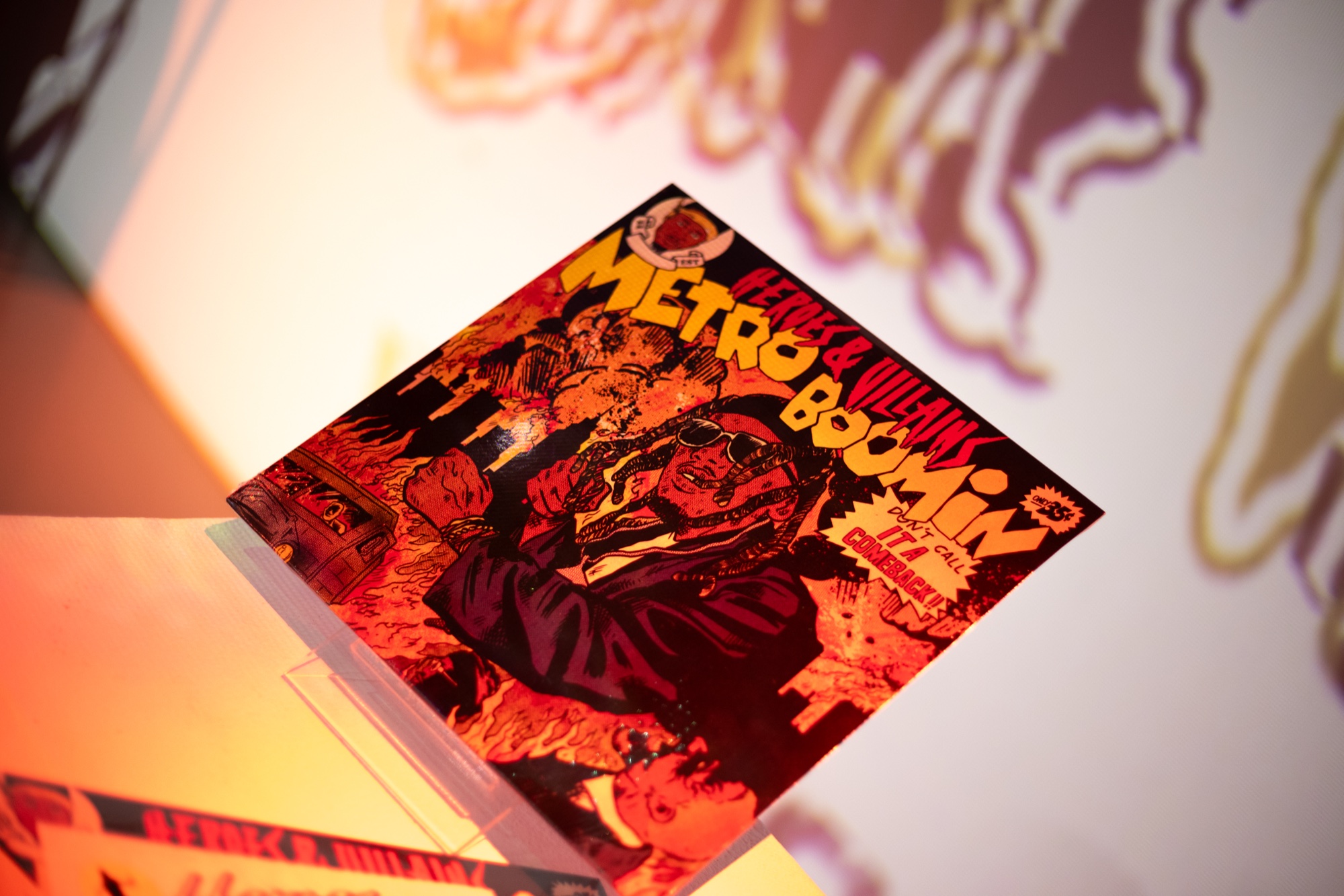 Metro Boomin comic style album cover in red and orange displayed on a lit plinth