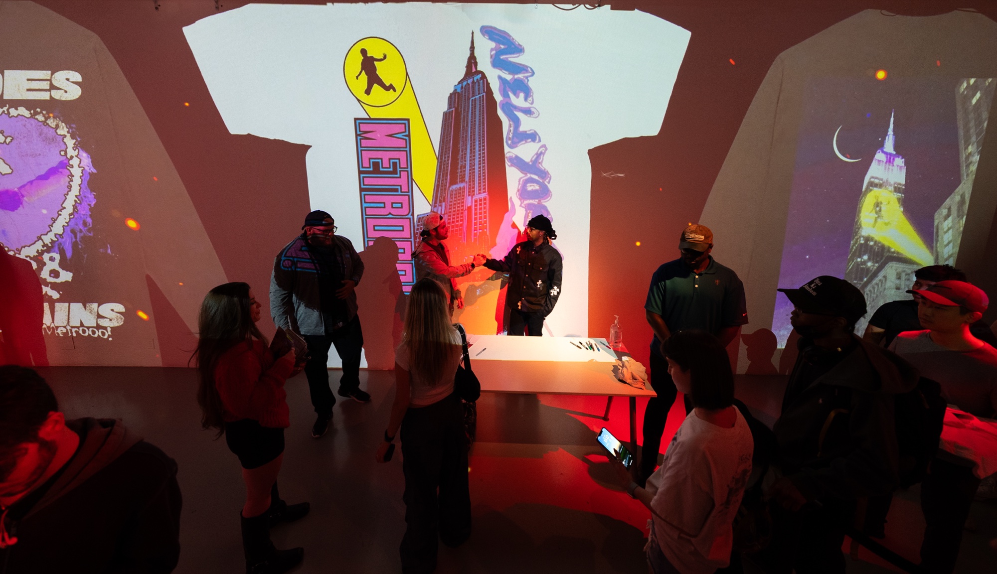 Guests gathered before a projected wall of a white shirt, the Empire State Building and Metro Boomin lettering