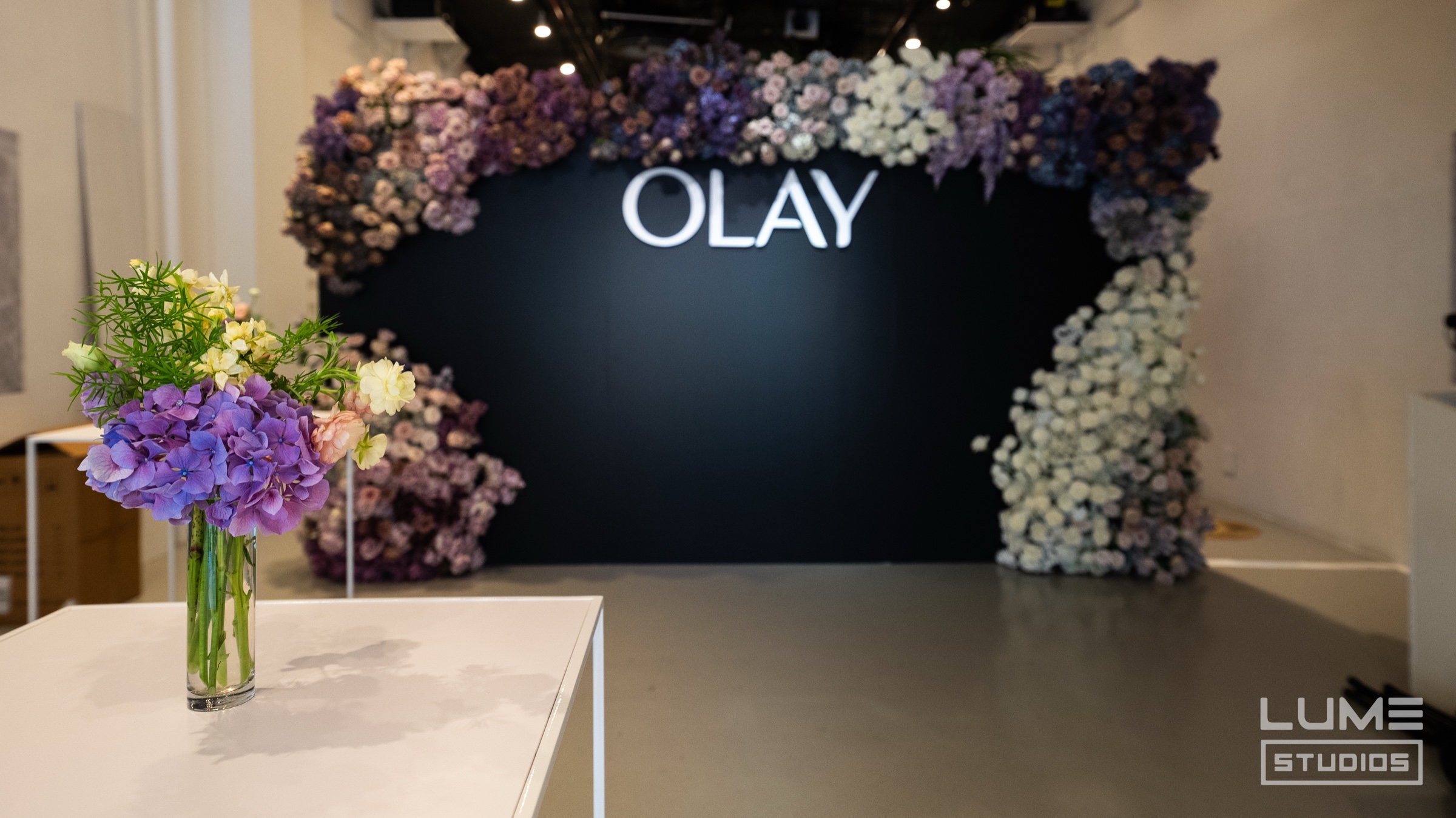Guest checks her phone beside a white wall reading #OlayBodyLabs
