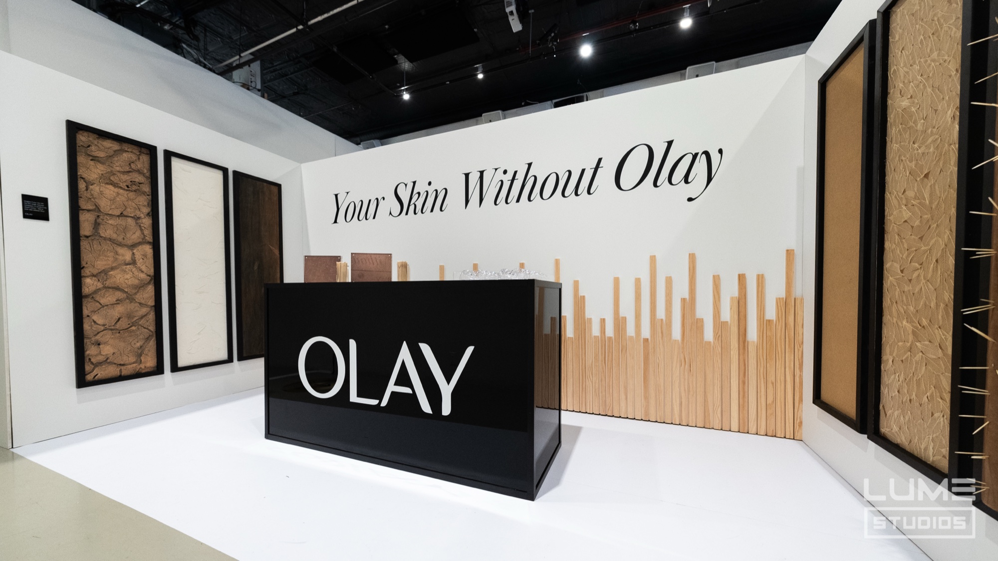 White showroom with a black Olay counter, wood slat wall and the words Your Skin Without Olay