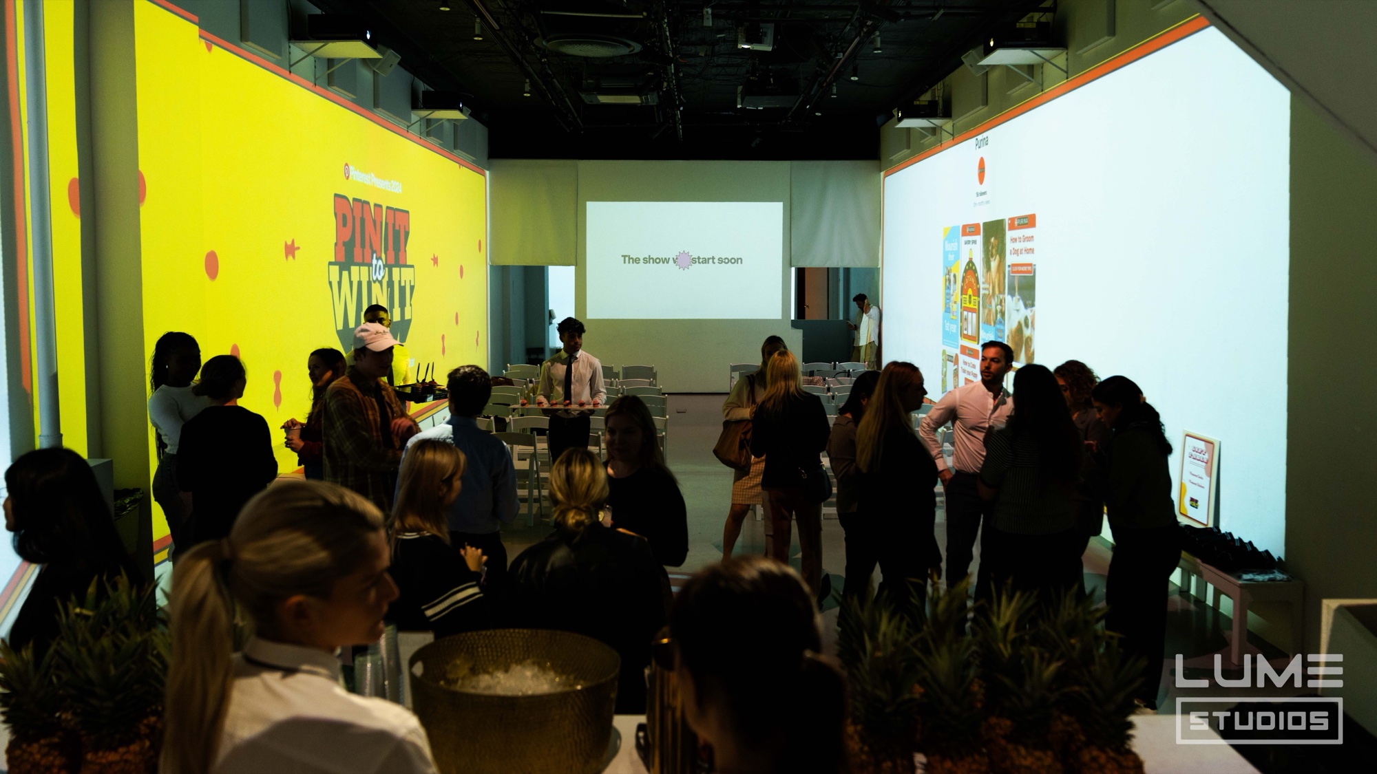 Guests mingle between bright Pinterest Presents projection walls before the show starts