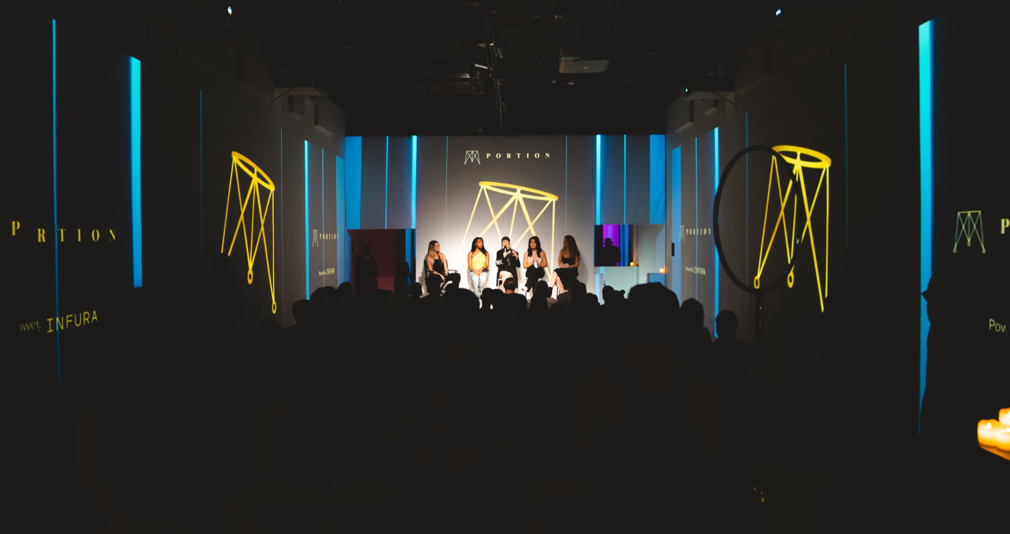 Guests stand beneath a projected Metaverse landscape at the Portion party