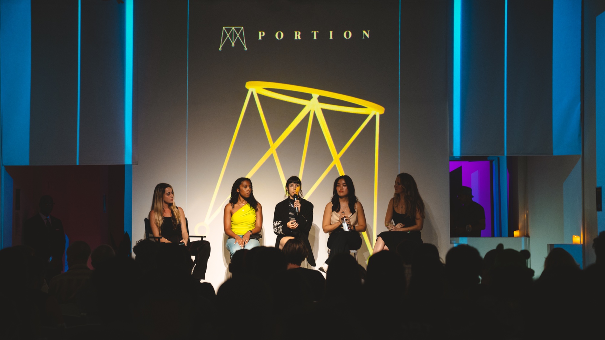 Five panellists seated on stage before a Portion logo and a yellow geometric backdrop, audience silhouetted in front
