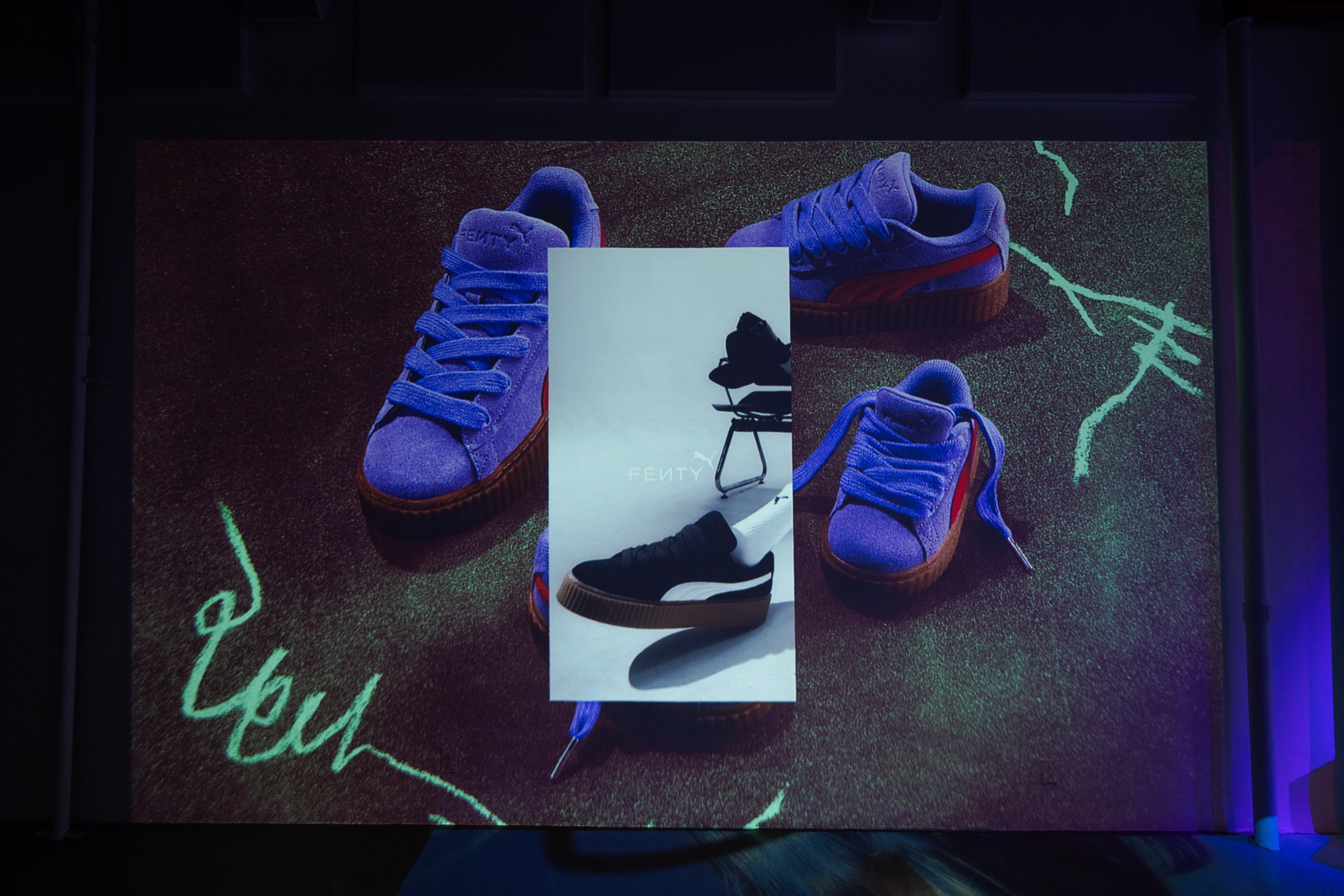 Guests silhouetted against a blue projection of the Creeper at Puma x Fenty