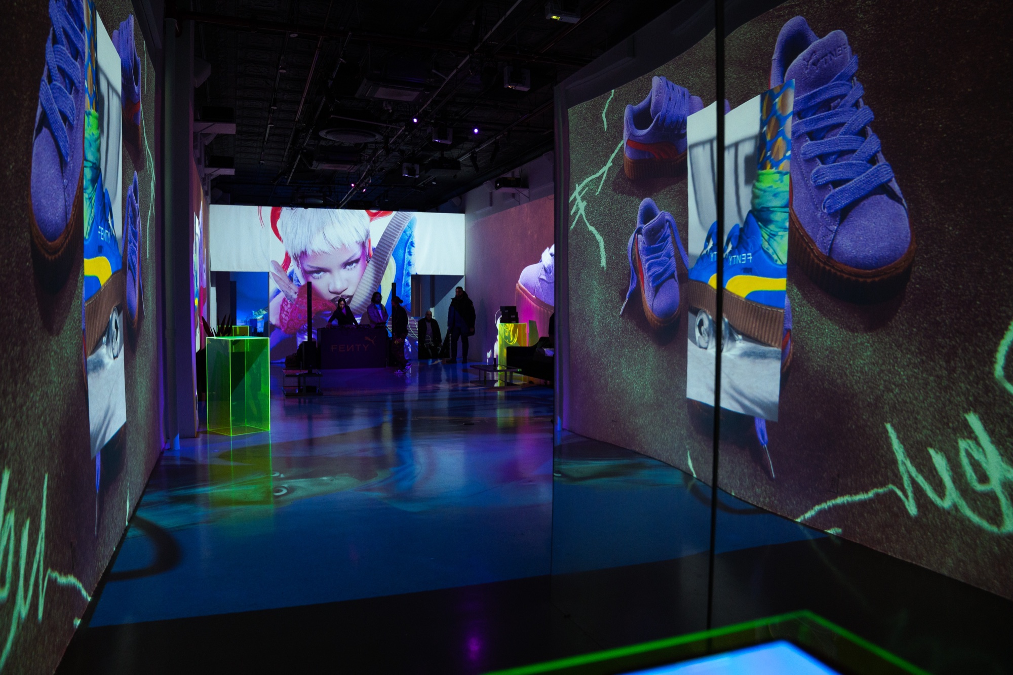 Purple suede sneakers and a cartoon face are projected on the walls of a dark corridor lit blue and green
