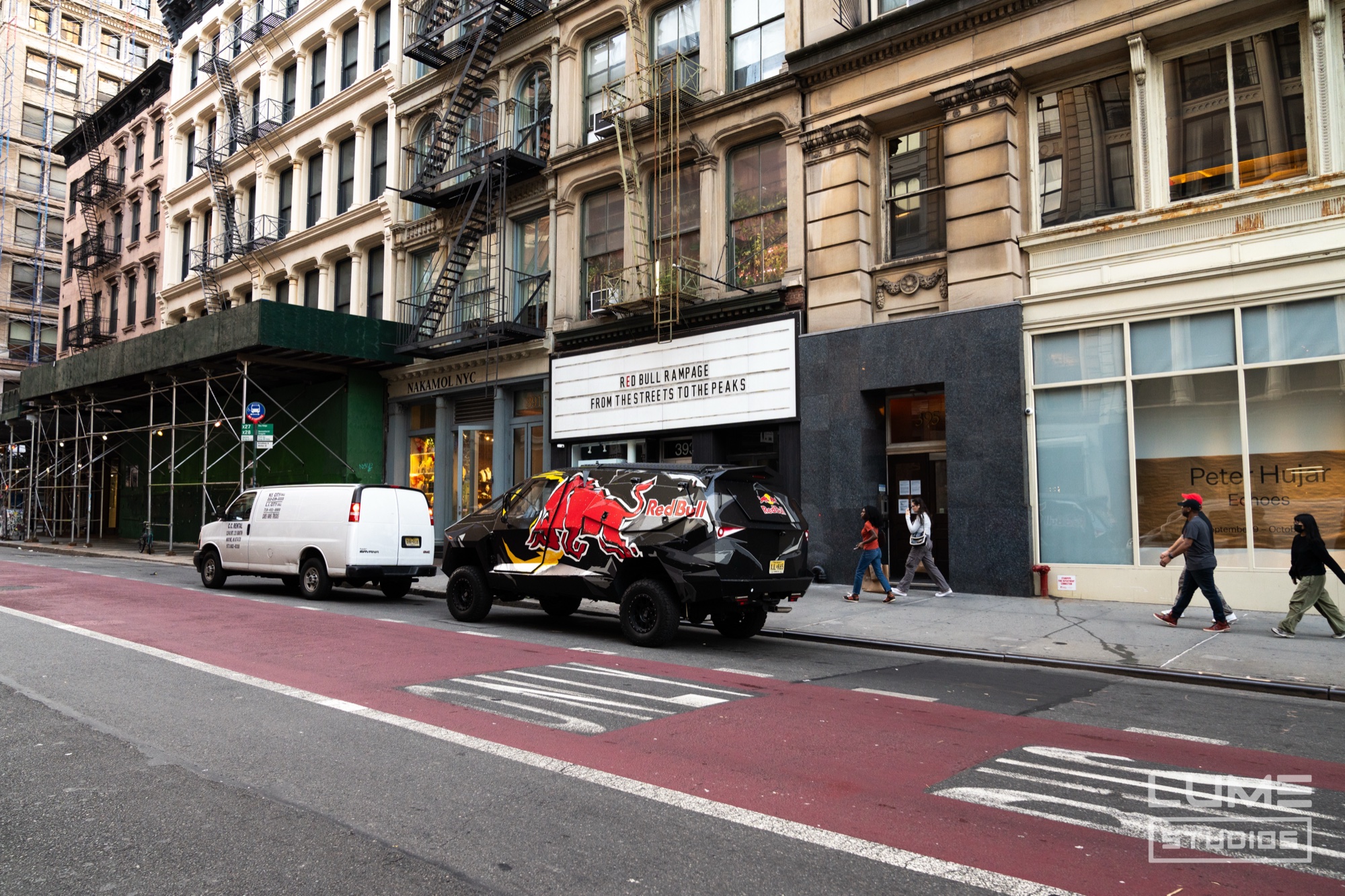 Red Bull wrapped truck parked on a Manhattan street beside a white van in front of cast iron buildings