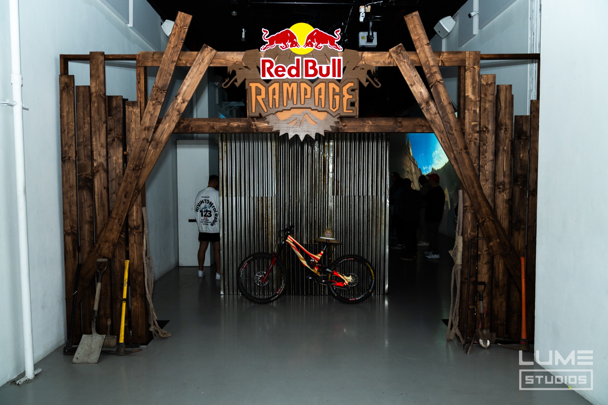 Mountain bike hangs on a corrugated wall inside a rough timber gateway topped by a Red Bull Rampage sign