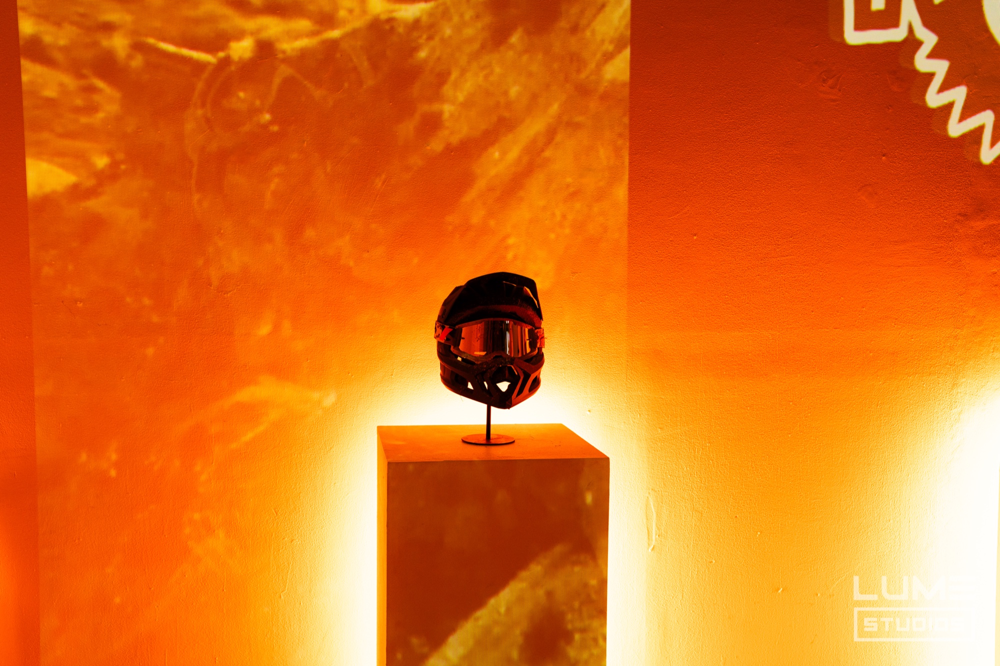 Mountain bike full face helmet on a plinth against a wall projected with orange rock textures