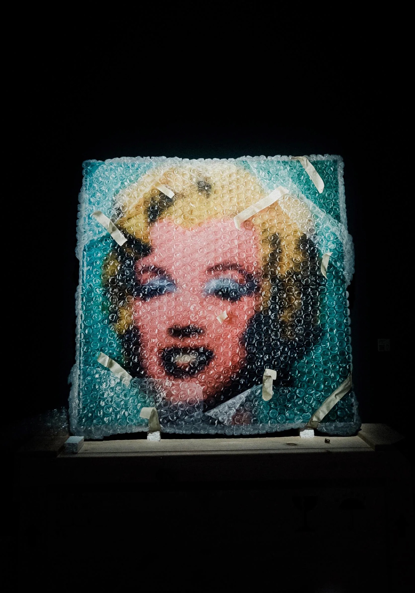 Marilyn Monroe portrait painted as if under bubble wrap, lit alone in the dark