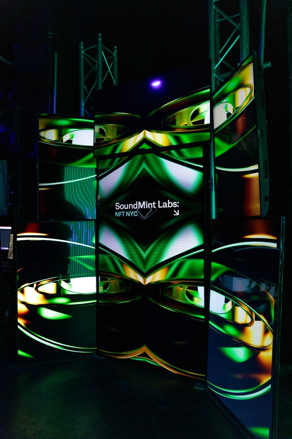 Screens forming a kaleidoscopic green sculpture display SoundMint Labs NFT NYC in a dark room