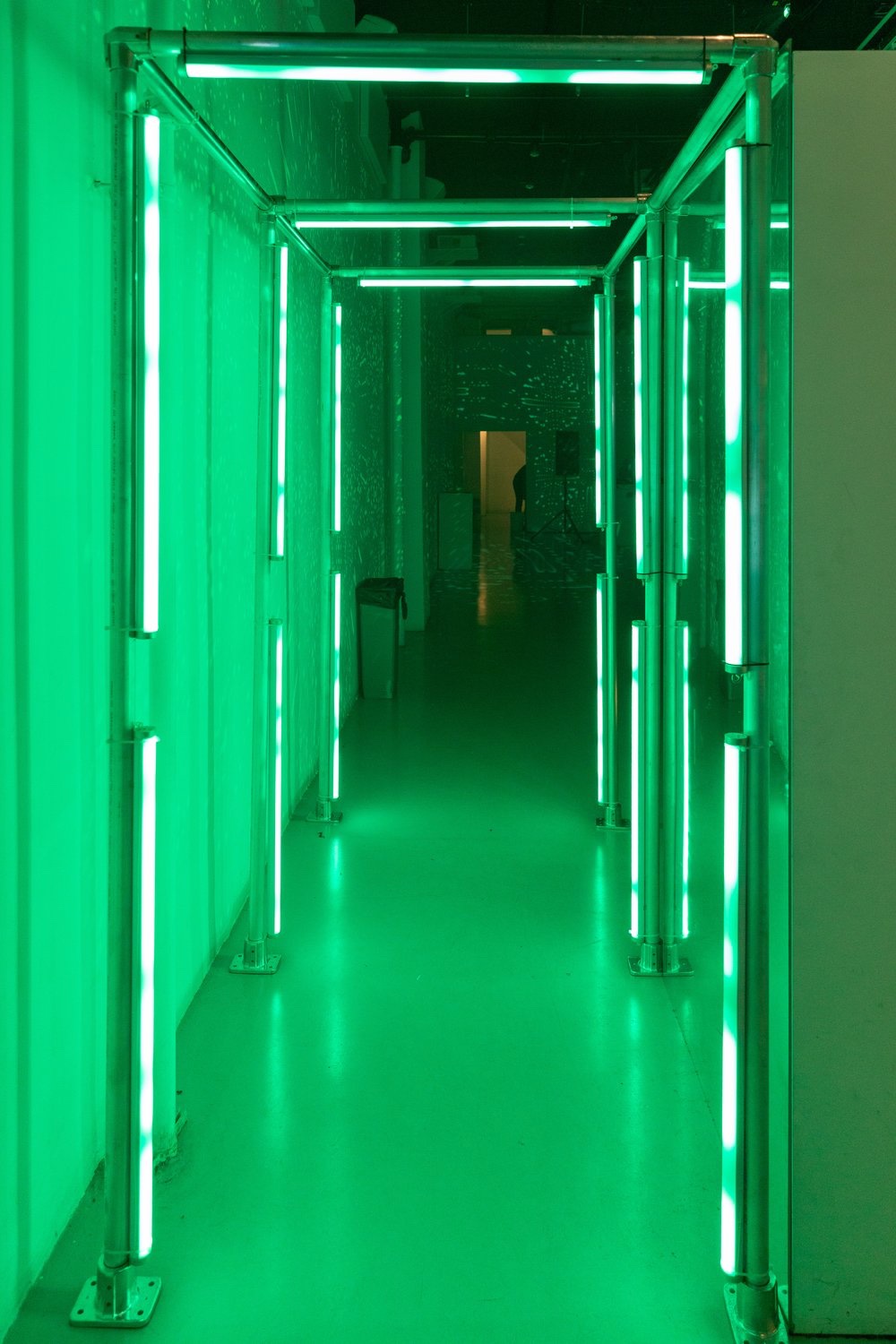 Corridor of metal poles and bright green light tubes leading into the SoundMint space