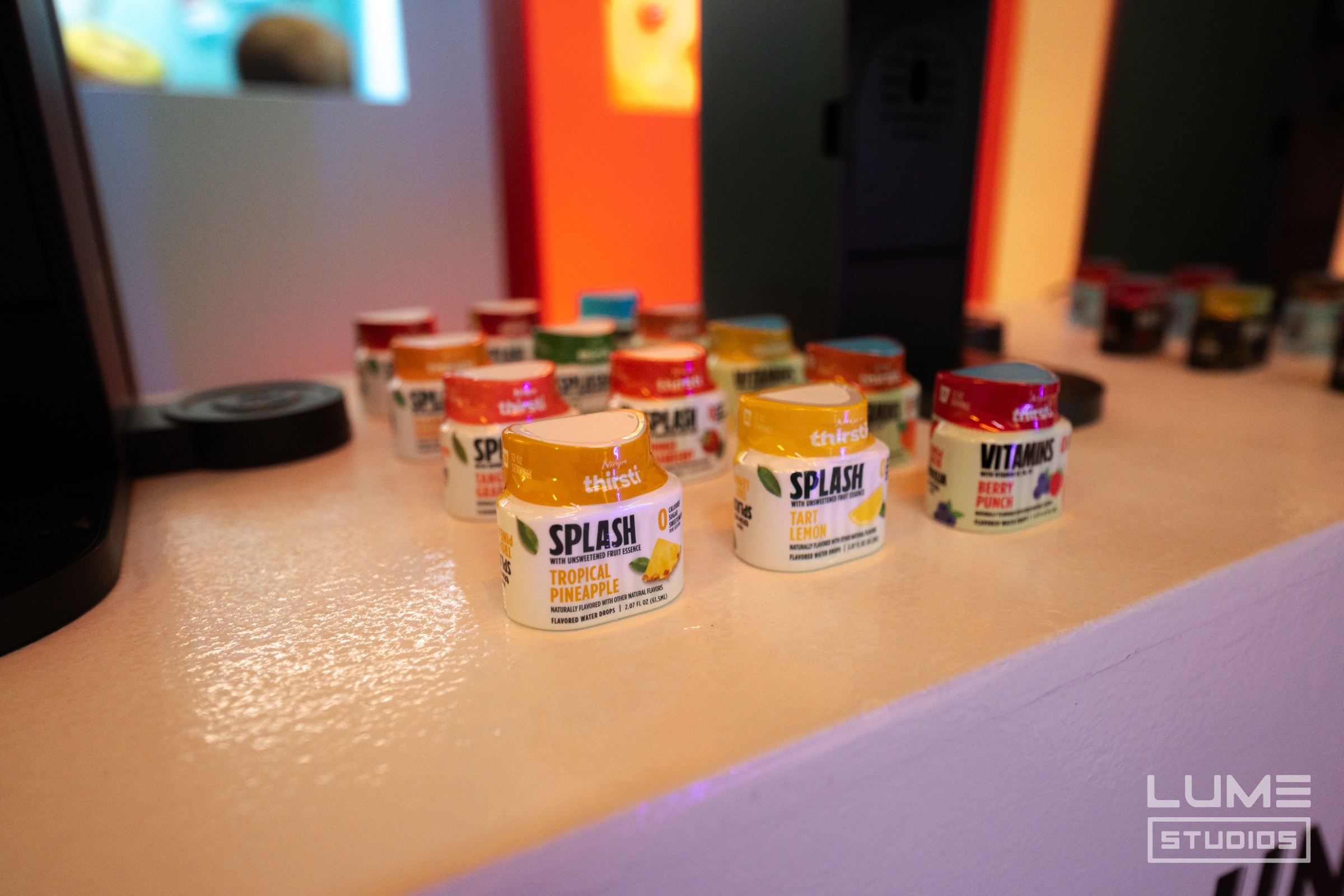 Ninja Thirsti drink machines stand on pedestals amid vivid pink and yellow wall projections