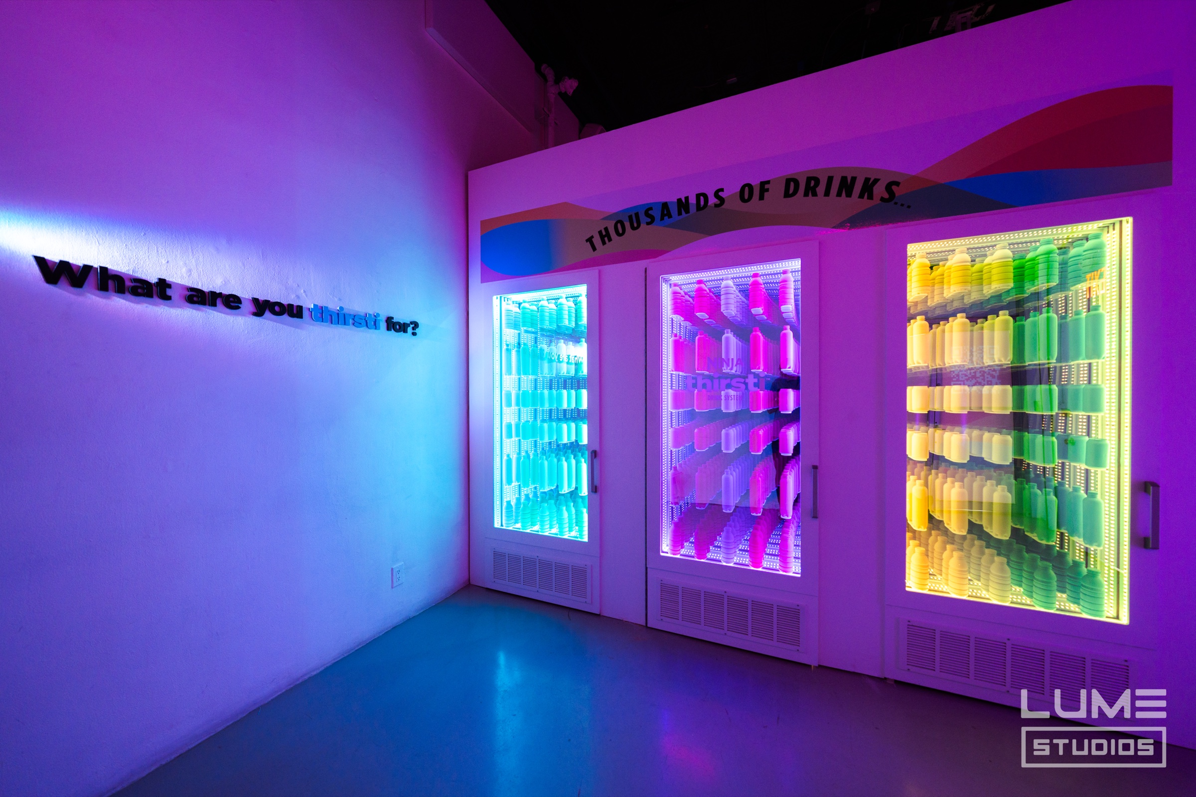 Branded pedestals display the Ninja Thirsti drink system throughout a room filled with projections at Lume Studios