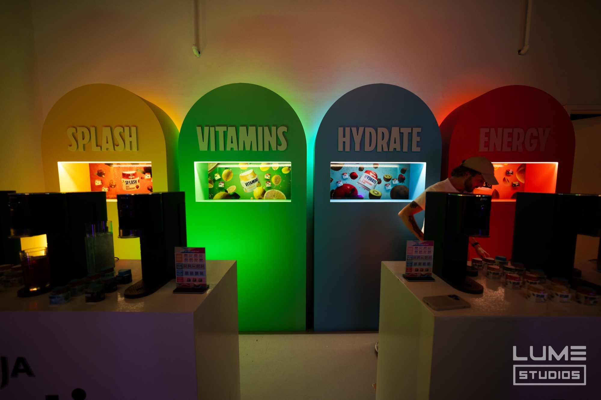 Four arched niches labelled splash, vitamins, hydrate and energy glowing yellow, green, blue and red