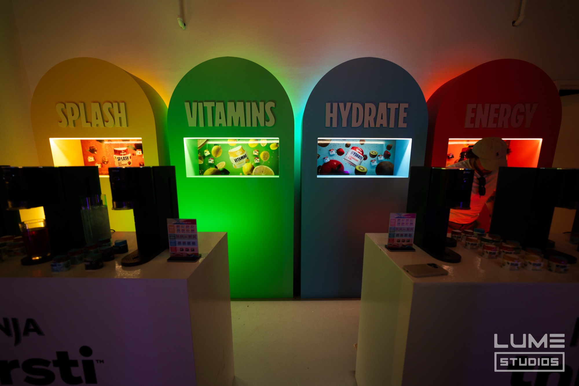 Four arched displays labelled Splash, Vitamins, Hydrate and Energy glow yellow, green, blue and red