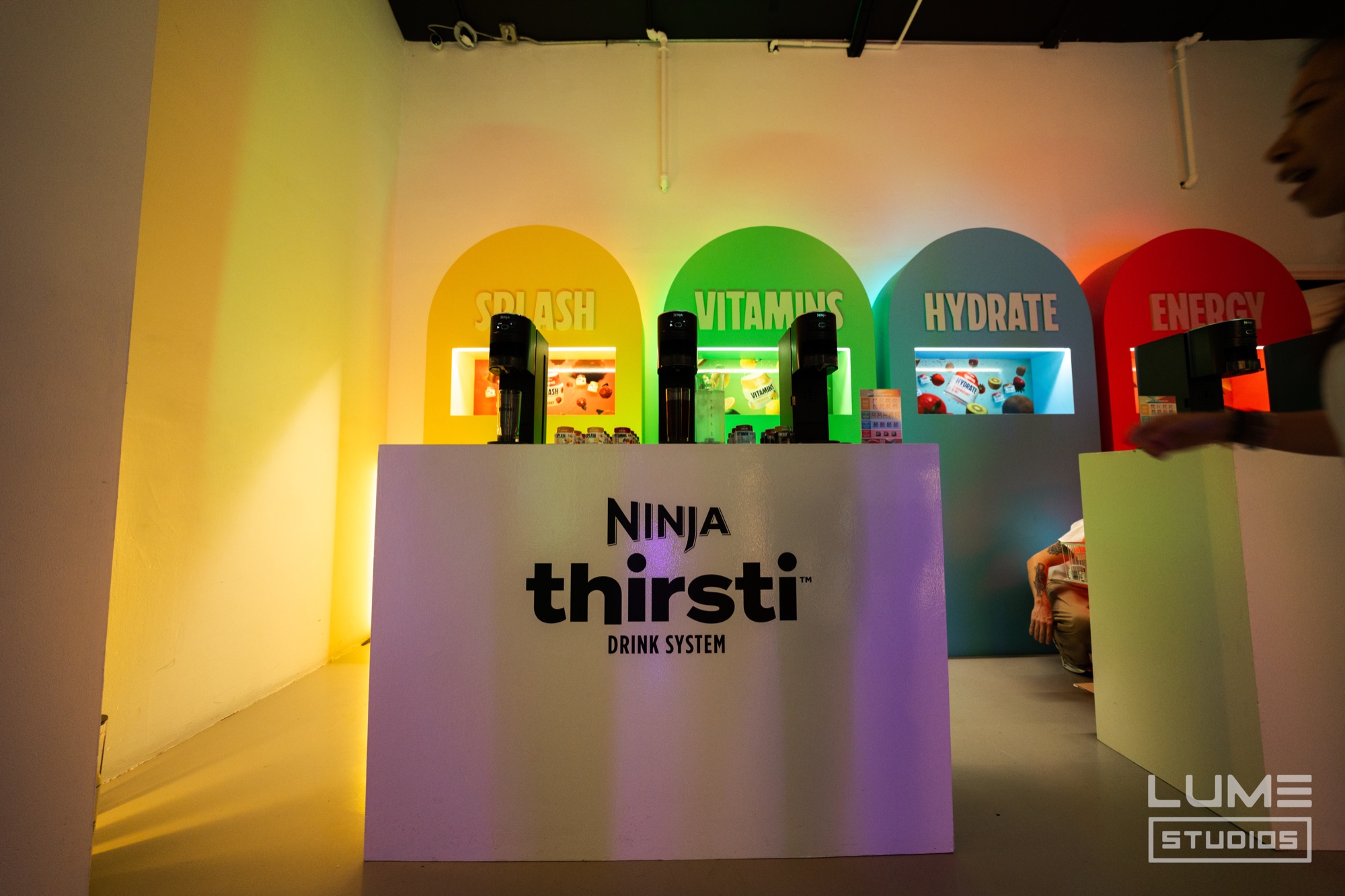 Ninja Thirsti counter with three machines under rainbow coloured arches reading Splash, Vitamins, Hydrate and Energy