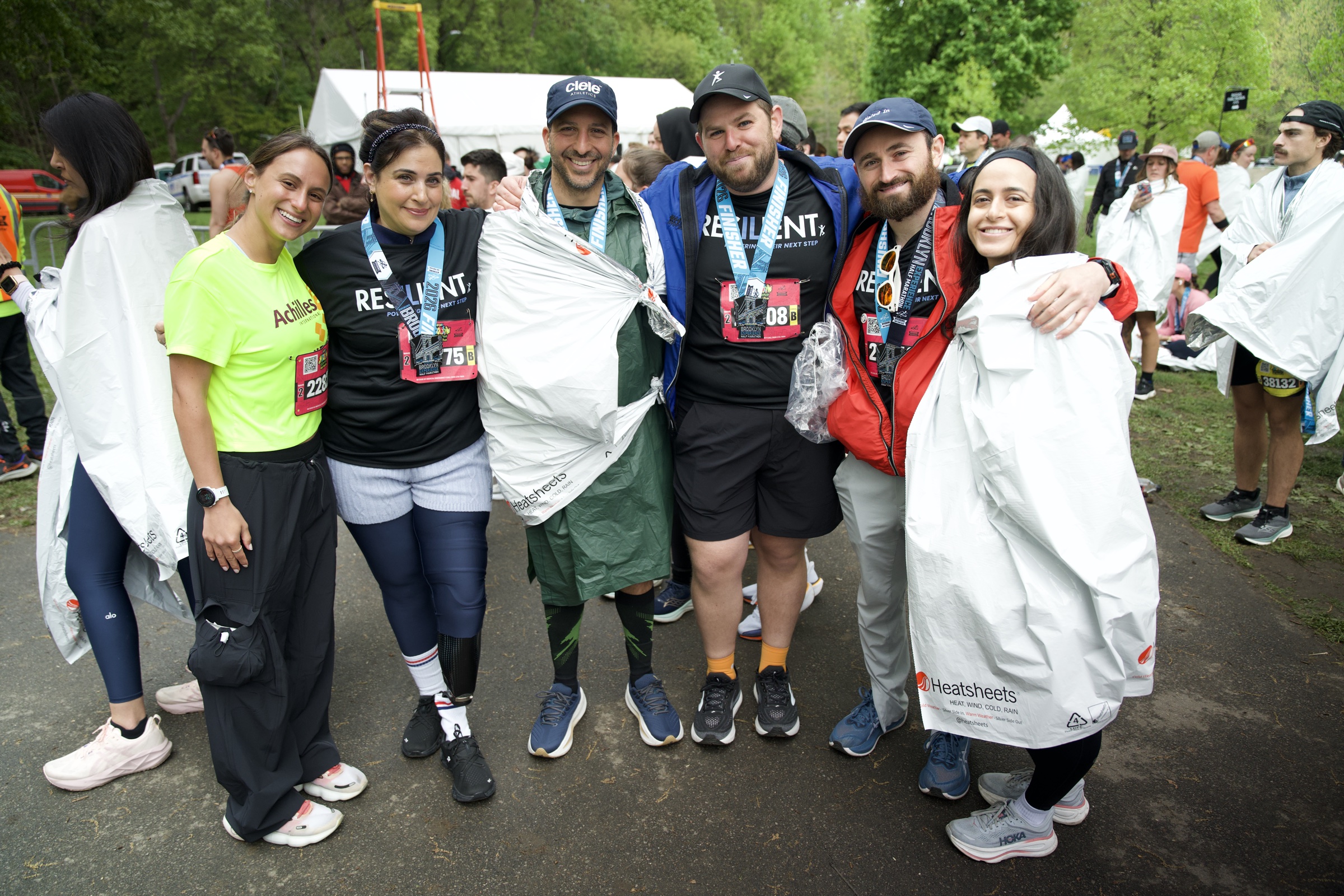 Finishers in foil blankets and medals stand arm in arm in Resilient shirts after the race