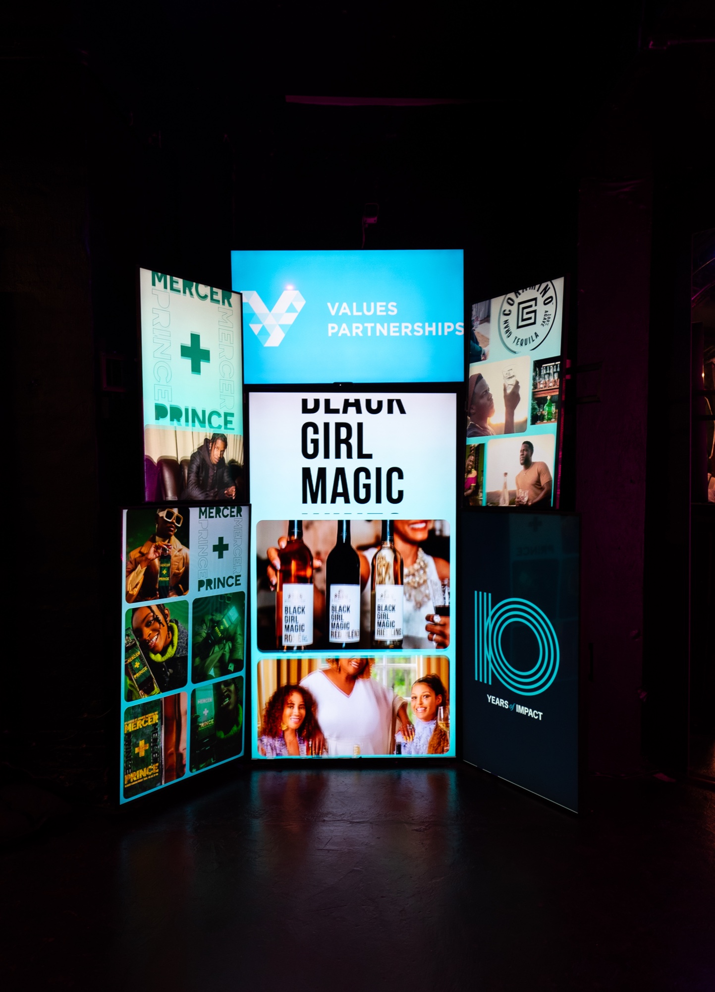 Backlit display tower with Values Partnerships branding, Black Girl Magic wine bottles and Mercer and Prince panels