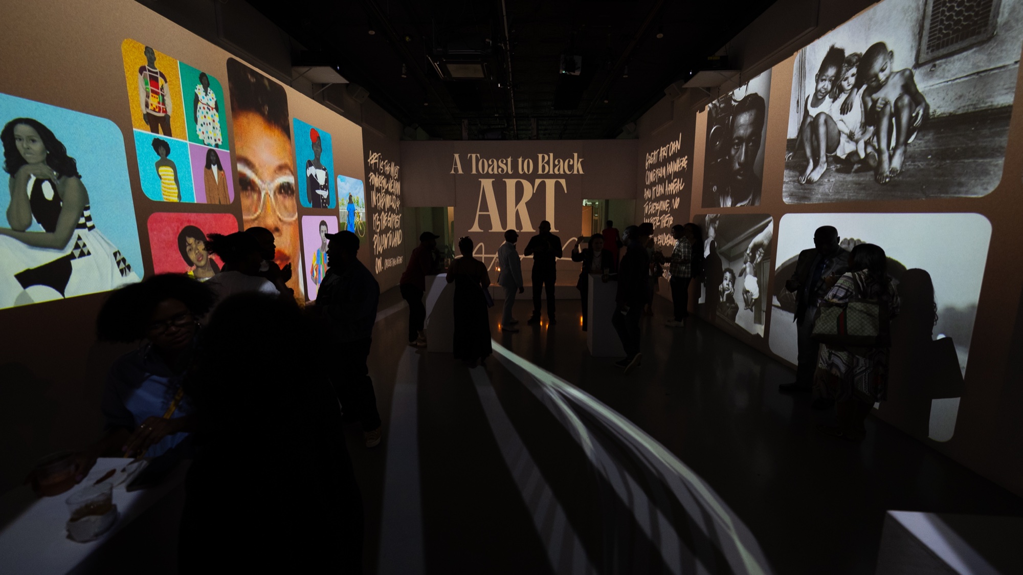 Guests in silhouette walk between walls projected with A Toast to Black Art and colourful portrait tiles
