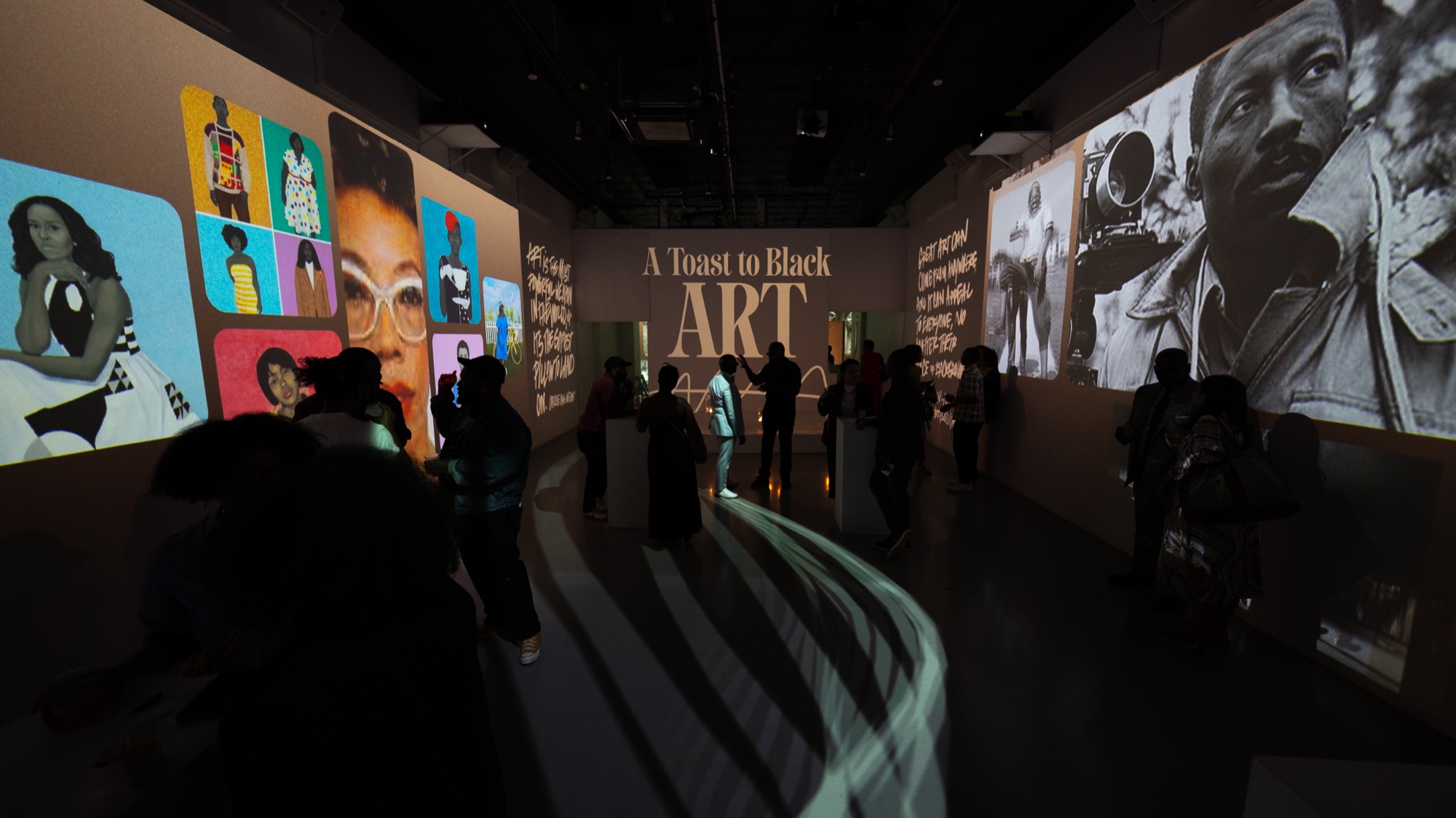 Guests in silhouette beneath projected portraits and the words A Toast to Black Art on the wall