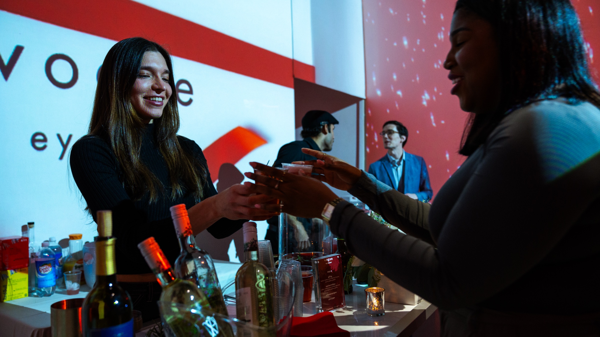 Guests in a red room with Vogue Eyewear projections and a model on a central screen
