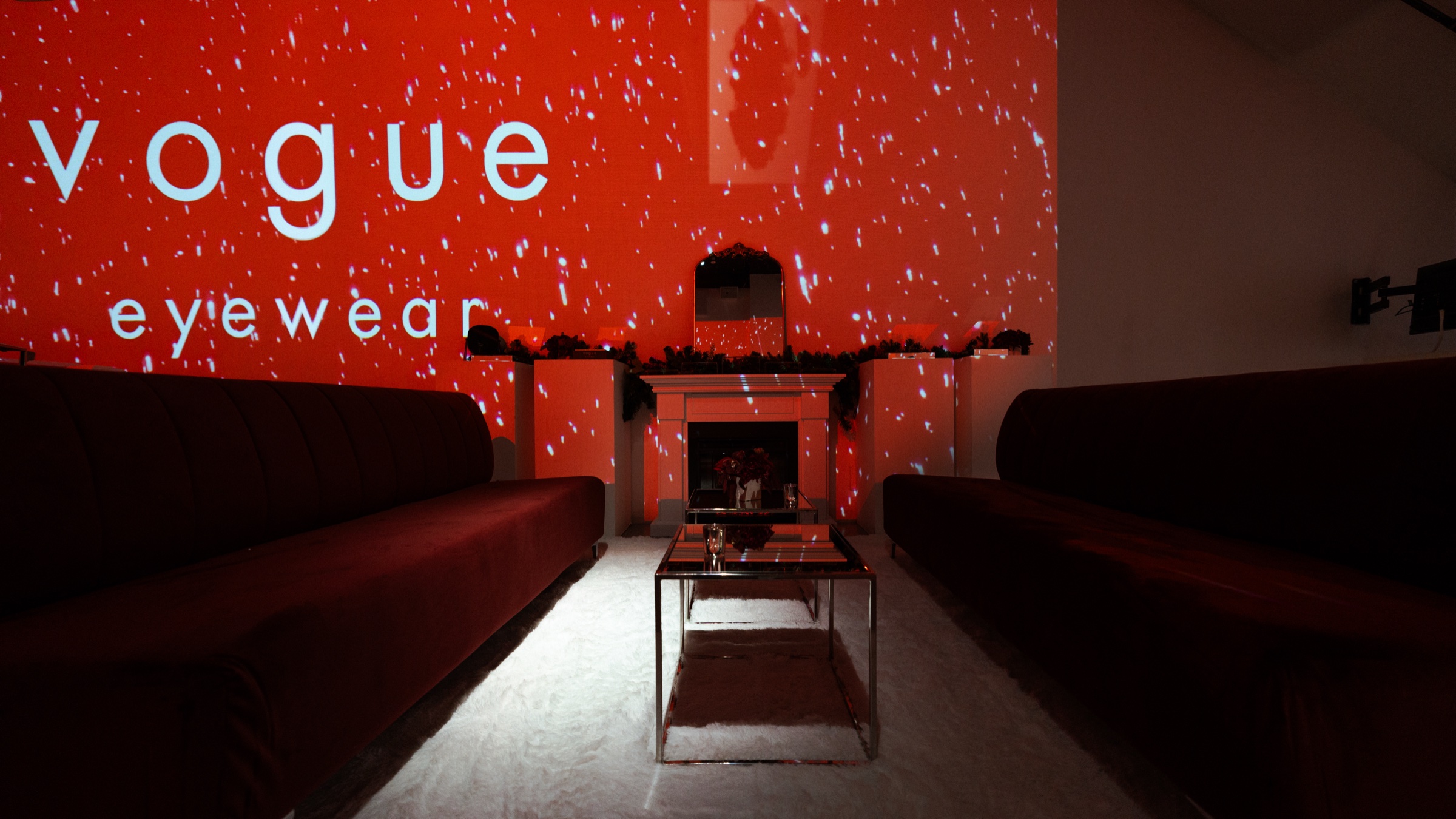 DJ in a grey suit at Pioneer decks beneath a red Vogue Eyewear wall projection