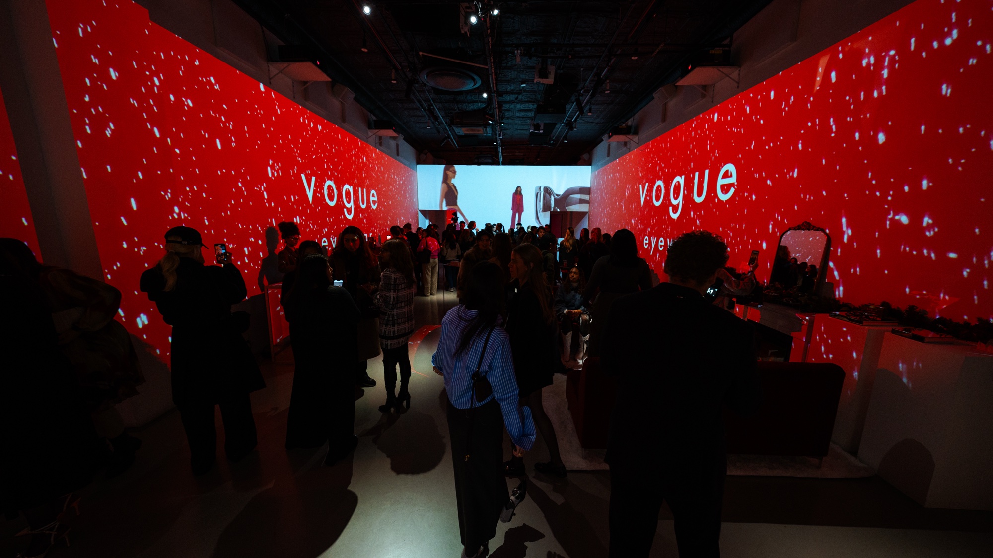 Guests filling a corridor lined with red walls of glowing white specks and the word vogue