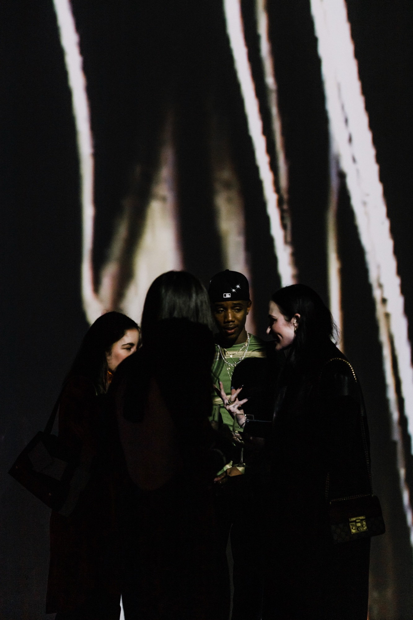 Four people huddle in conversation before a wall of projected white streaks on black