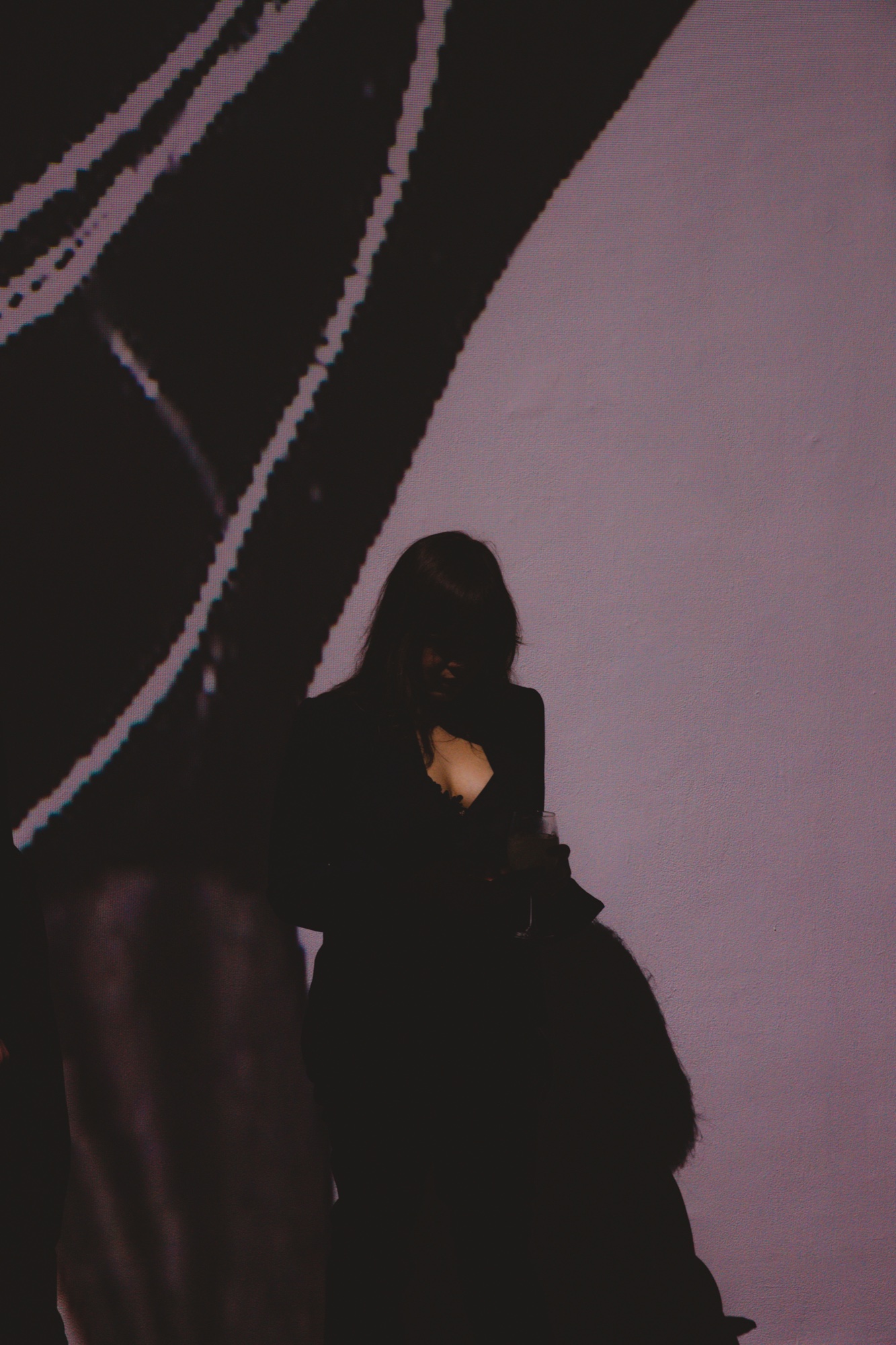 Silhouette of a woman on her phone against a mauve wall crossed by a giant projected black line drawing