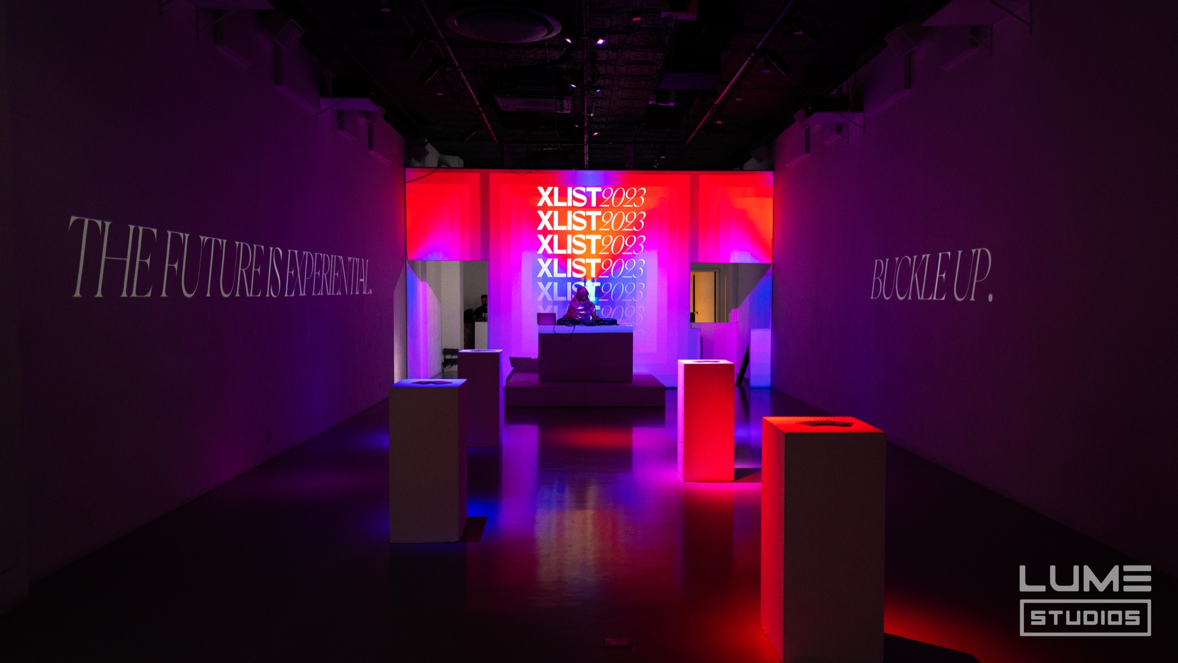 XLIST 2023 stage in orange and blue gradients with glowing pedestals and “the future is experiential”