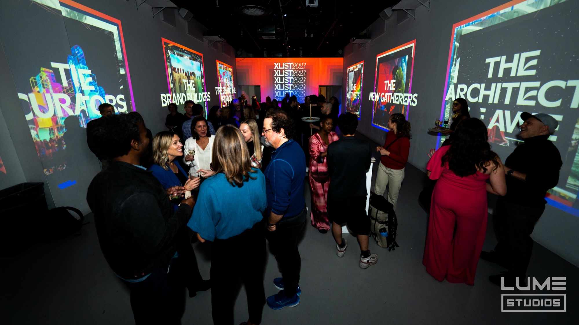 Guests mingling before projected panels reading The Curators, Brand Builders, The New Gatherers and The Architects